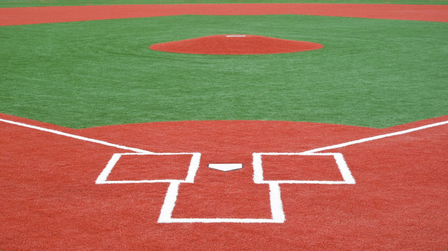 View of a baseball field by AZ Turf and Pavers, showing home plate, batter’s boxes, and the pitcher’s mound, with bright green artificial turf and red dirt-like areas marked by crisp white lines.